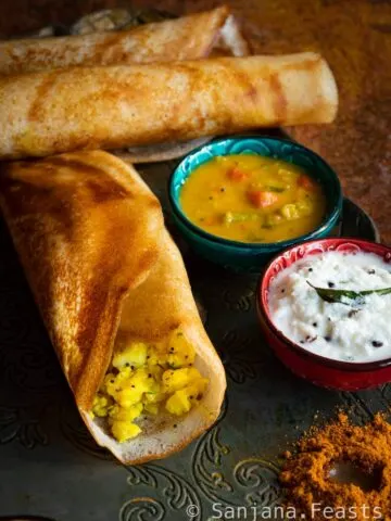 A platter of Indian breakfast masala dosa with coconut chutney and sambar in bowls