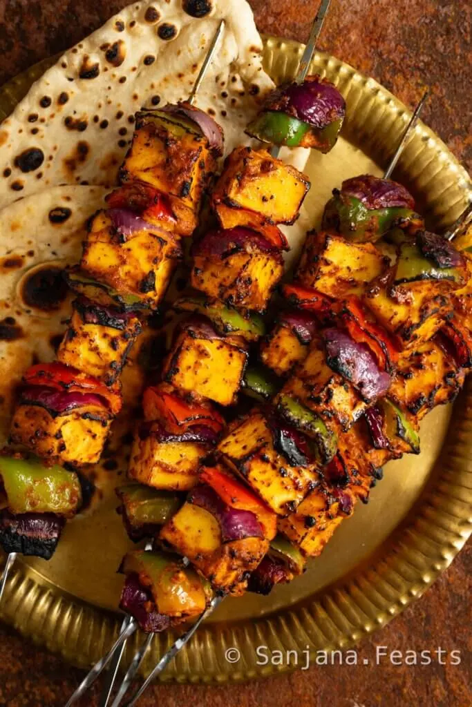 Paneer Tikka Kebabs on a platter with fresh naan bread